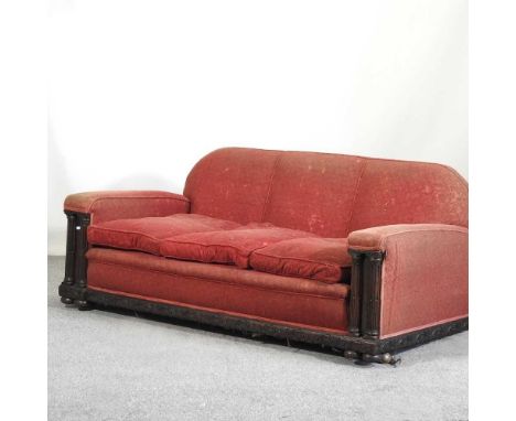 An Art Deco three piece suite, upholstered in red, with oak column arms, comprising a sofa, 182cm wide and a pair of armchair