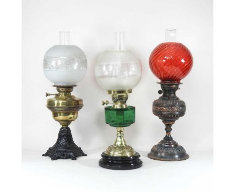 A 19th century brass oil lamp, with a red glass shade, 53cm high, together with two other various oil lamps (3)