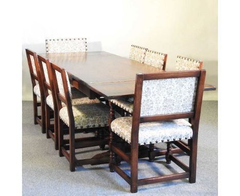 A modern oak draw leaf dining table, on a trestle base, together with a set of eight upholstered dining chairs, on bobbin tur