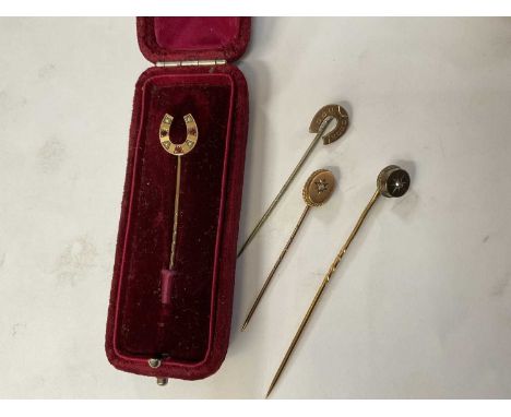 Four Victorian stick pins to include a 9ct gold ruby and seed pearl horseshoe stick pin, two rose cut diamond and gold stick 
