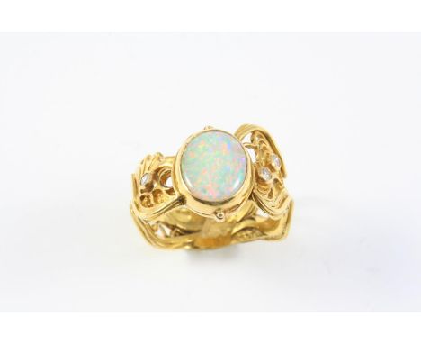 AN OPAL AND 22CT GOLD RING BY LUCY COPLESTONE the oval-shaped opal is set within an ornate gold mount set with three circular