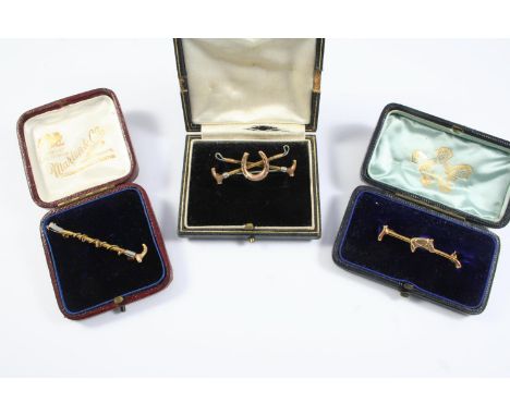 HUNTING INTEREST: a gold brooch, depciting a horseshoe with two riding crops, 4cm wide, together with a gold riding crop broo
