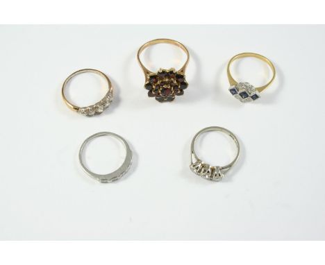 FIVE ASSORTED GOLD AND GEM SET RINGS including a diamond three stone ring, set in white gold and platinum, size L 1/2, a garn