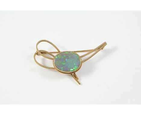 A BLACK OPAL AND GOLD BROOCH the oval-shaped solid black opal is within a yellow gold abstract mount, 5cm long