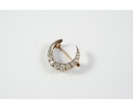 A VICTORIAN DIAMOND CRESCENT BROOCH set with graduated old cushion-shaped diamonds, in silver and backed in gold, 2.5cm wide