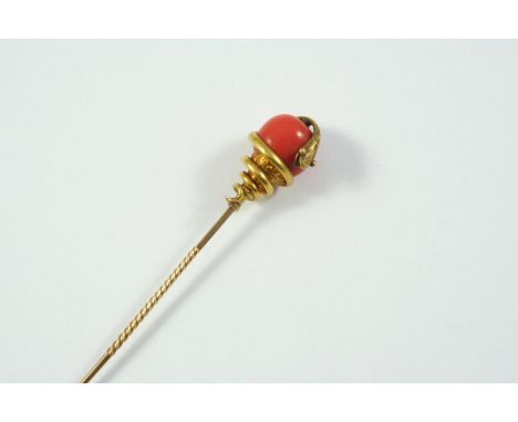 A CORAL AND GOLD SNAKE STICK PIN mounted with a coral bead entwined by a gold snake, 8.5cm long