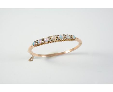 AN EARLY 20TH CENTURY OPAL AND DIAMOND HALF HINGED BANGLE mounted with seven graduated circular cabochon solid white opals, e