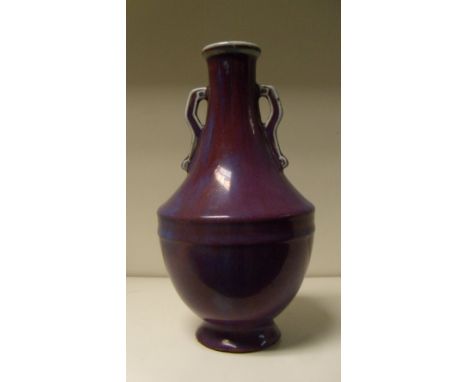 A purple flambe vase, the bracket handled neck flaring to a moulded band to the top of the hemispherical body raised on flare