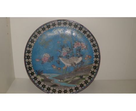 An early 20th century cloisonne enamel dish, worked with two cranes below bamboo by a stream against a turquoise ground withi