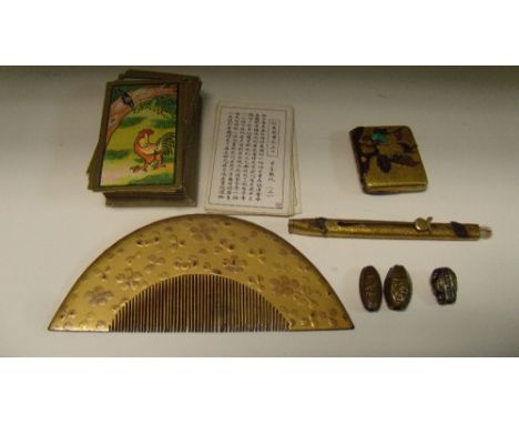 Three ojime, a lacquer comb, a retractable brush, a vesta and a pack of cigarette cards, the three ojime variously cast, the 