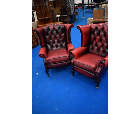 A pair of red leather button back wing armchairs