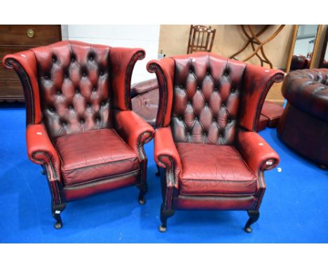 A pair of red leather button back wing armchairs