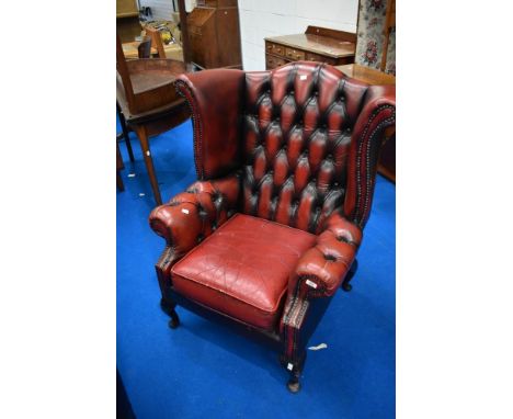 A red leather button back wing armchair
