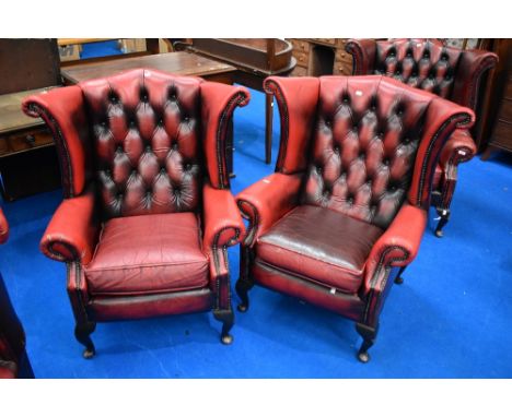 A pair of red leather button back wing armchairs