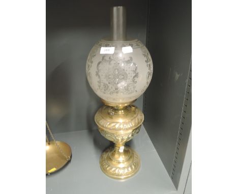 An antique oil burning lamp with impressed brass body and etched glass shadeSmall nibble chips on base of shade where it sits