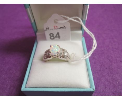 A lady's dress ring having a central opal with cubic zirconia set shoulders on a white metal loop stamped 925, size J/K