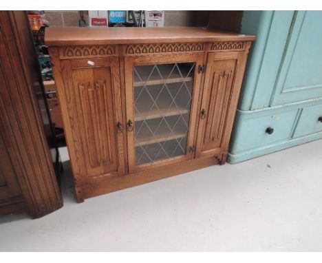 An oak side board with waxed finish and leaded light style door