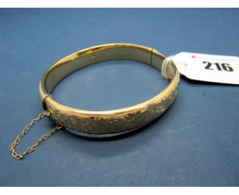 A 9ct Gold Bangle, leaf scroll engraved to the front, hinged to snap clasp. 