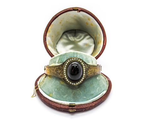 A XIX Century Bangle, oval cabochon set to the centre, hinged to snap clasp, in a fitted case. 