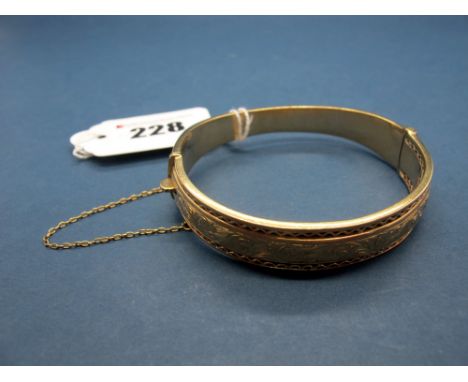 A 9ct Gold Bangle, pierced and scroll engraved to the front, hinged to snap clasp. 