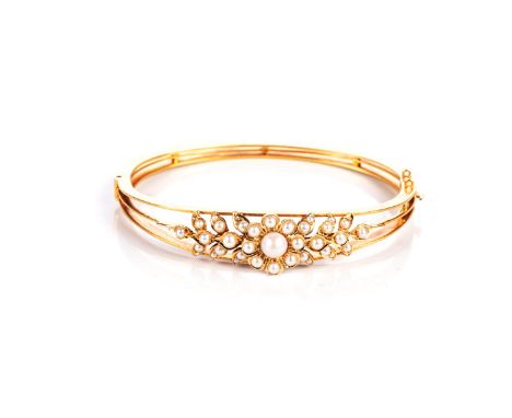 A VICTORIAN SEED PEARL HINGED BANGLE Oval, centred with a fower head and foliage embellished with seed pearls, acid tested as