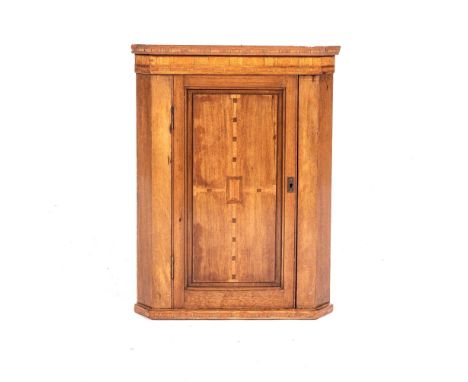 A GEORGE III HANGING CORNER CUPBOARD The outswept cornice with canted corners above a plain frieze, a panelled door below enc