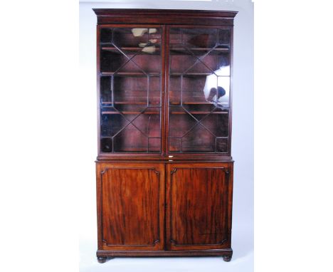 A late Georgian mahogany bookcase cabinet, the upper section having twin astragal glazed doors enclosing fitted interior with