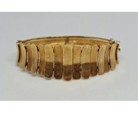 A hallmarked 9ct yellow gold hinged bangle, featuring graduated textured metalwork to front, weight approx. 32.4g. IMPORTANT:
