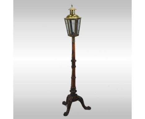 A brass standard lamp, in the form of a lantern, mounted on a carved oak tripod base, 153cm high