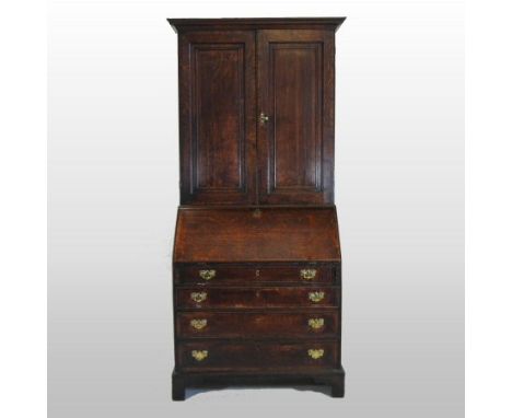 An 18th century oak bureau cabinet, the upper section enclosed by a pair of panelled doors, with a hinged fall below, on brac