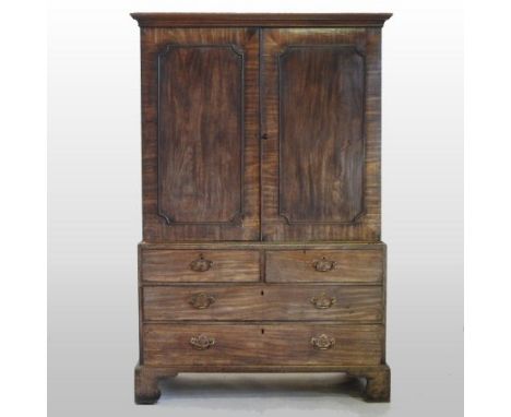 A George III mahogany linen press, enclosed by a pair of panelled doors, above an arrangement of drawers, on bracket feet, 12