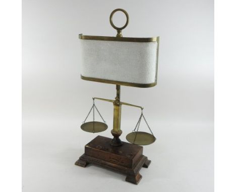A set of early 20th century brass scales, with a light shade, on a wooden base, 54cm high