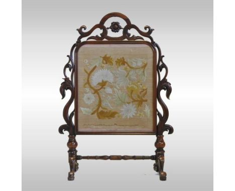 A Victorian carved walnut fire screen, of openwork design, with a woolwork panel, 89cm