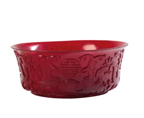 PEKING RUBY-GLASS BOWL, the sides carved in relief with stylised chilongs and shou medallions, 19cm diam