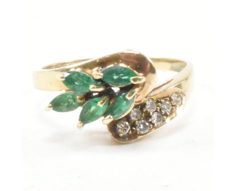 A hallmarked 9ct yellow gold, diamond and synthetic emerald crossover ring. The ring having a cluster of marquise cut green s