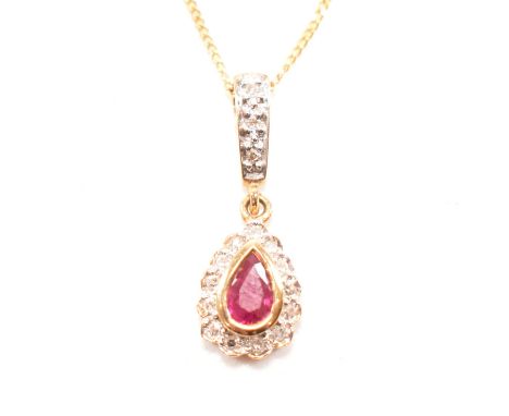 A vintage 9ct yellow gold, ruby and diamond halo pendant and chain necklace. The pendant having a bezel set pear cut ruby set