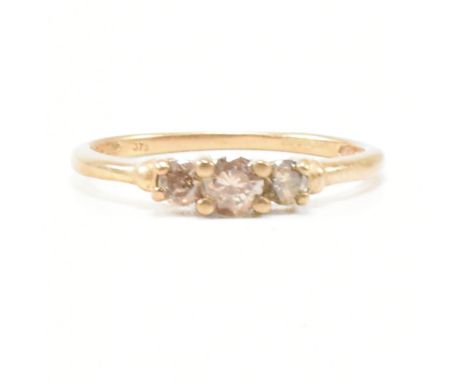 A hallmarked 9ct gold and diamond three stone ring. The ring set with three round brilliant cut champagne colour diamonds. Es