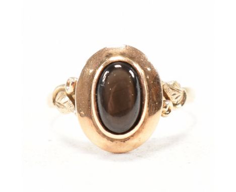 A vintage black star sapphire cabochon ring. The ring having a black star sapphire oval cabochon to a halo head and foliate s