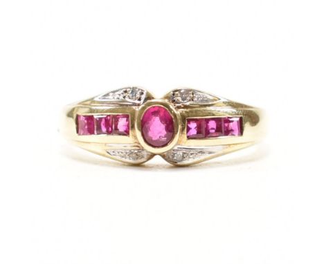 A hallmarked 9ct yellow gold, ruby and diamond cluster ring. The ring having a central bezel set oval cut ruby flanked by thr