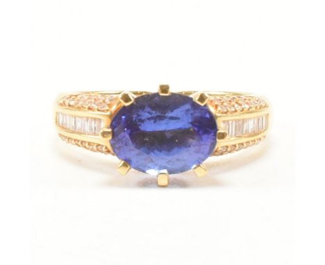 A hallmarked 18ct yellow gold, tanzanite and diamond ring. The dress ring having a central oval cut exaggerated prong set blu