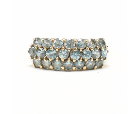 A hallmarked 9ct yellow gold and topaz cluster ring. The ring having three rows of round cut blue topaz to double split shoul