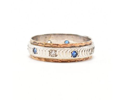 A hallmarked 9ct bi colour gold eternity ring. The two tone ring set with round cut white and blue gem stones to a white gold