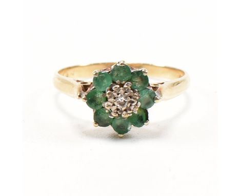 A hallmarked 9ct gold and emerald cluster ring. The ring set with a central illusion set diamond framed by round cut emeralds