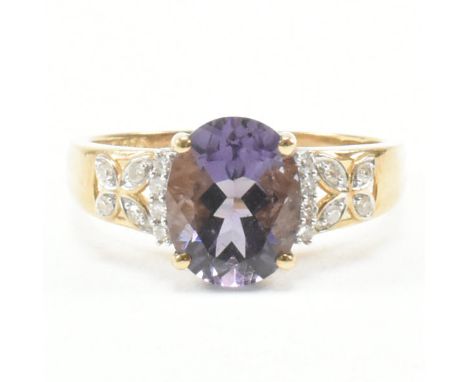 A hallmarked 9ct yellow gold, amethyst and diamond ring. The ring having a central oval cut amethyst flanked by a row of four