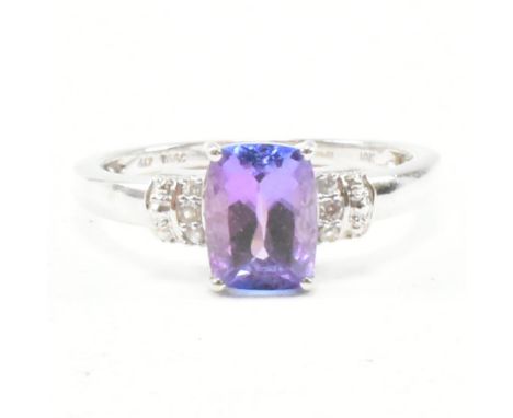 A hallmarked 9ct white gold tanzanite and gem set ring. The ring having a rectangular cut tanzanite flanked by a cluster of a