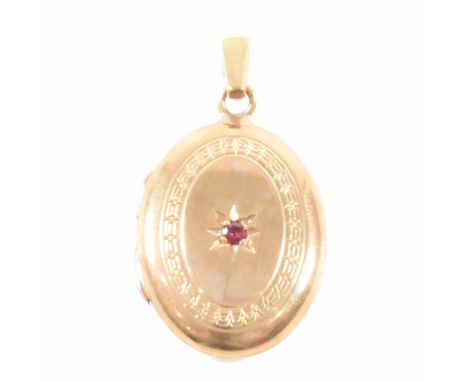 A hallmarked 9ct gold and ruby locket necklace pendant. The pendant of oval form having a central round cut star set ruby and