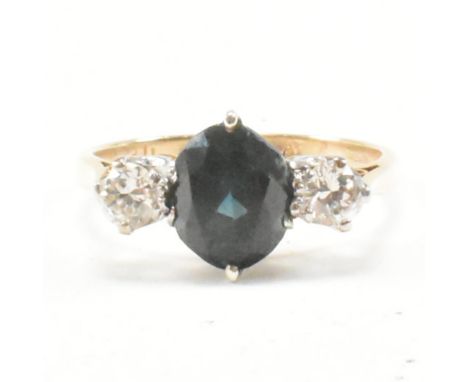 A hallmarked 14ct yellow gold, diamond and sapphire three stone ring. The ring having a central oval cut sapphire flanked by 