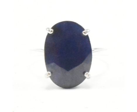 A hallmarked 9ct white gold and sapphire dress ring. The ring having an oval cut claw set sapphire to pinched shoulders and s