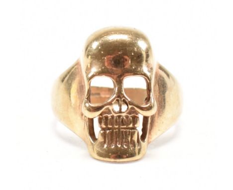 A vintage hallmarked 9ct yellow gold skull ring. The ring in the form of a human skull with pierced detailing on a tapered sh