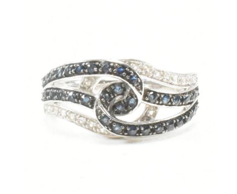 A white gold blue and white stone crossover ring. Stamped 14k. Weight 3.8g. Size N.&nbsp;All weights, measurements and sizes 